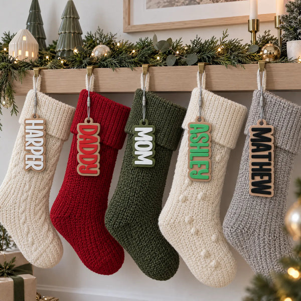 Block Letter stocking name tags on a row of Christmas stockings along a mantel with a decorated tree