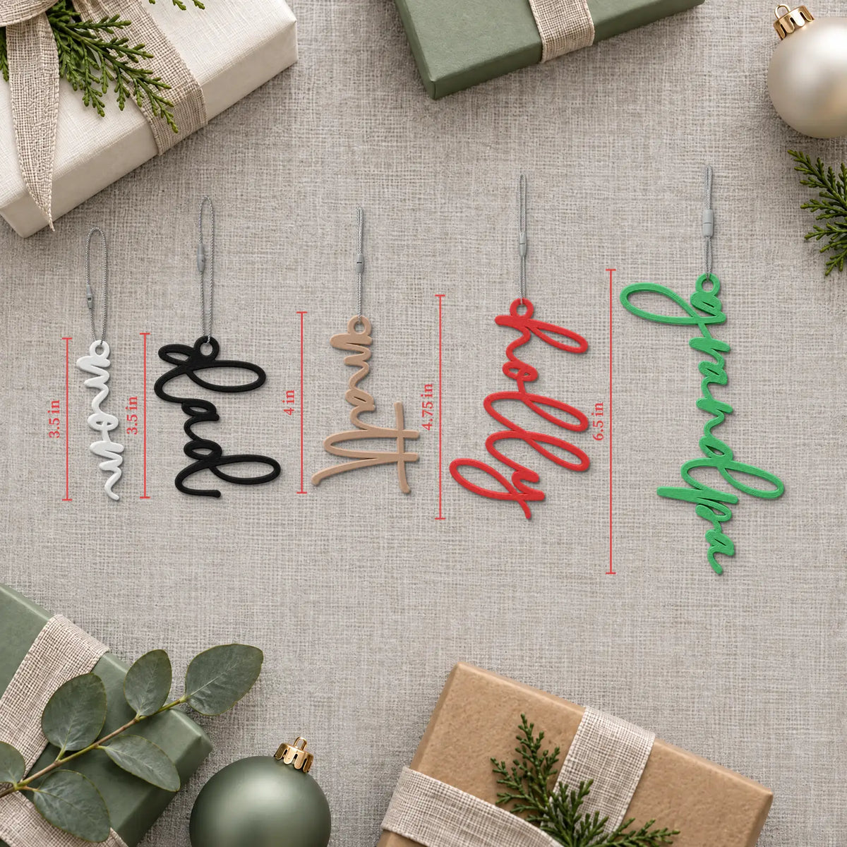 Flat lay of Lowercase Script stocking name tags with ornaments, showing how tag length changes with each name